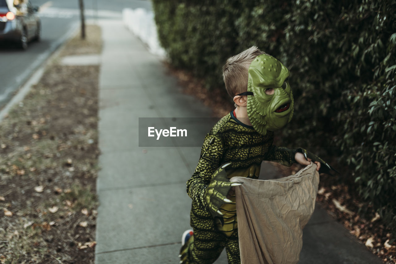 School aged boy dressed as monster trick-or-treating during halloween