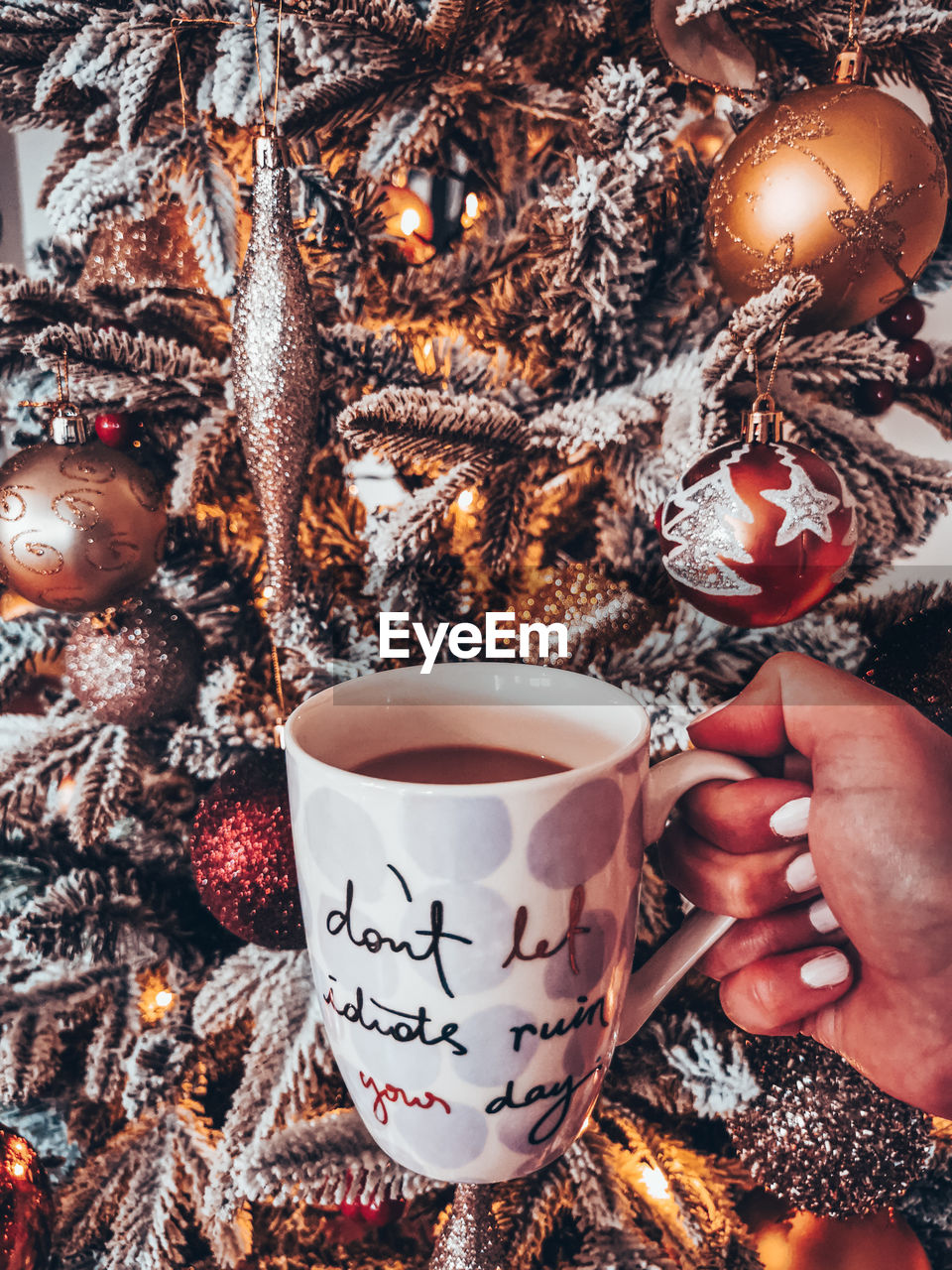 Close-up of hand holding coffee with christmas tree