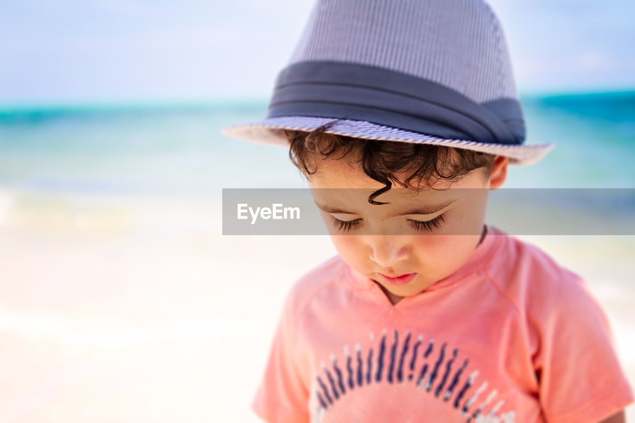 Little boy with curly hair walking a the beach in the caribbean