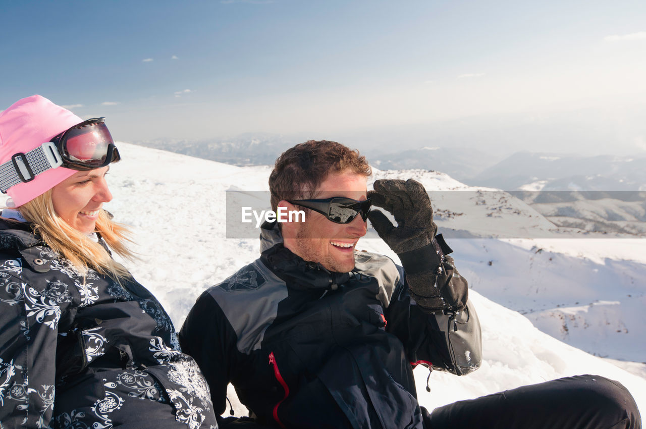 Happy mid adult couple looking away on snowcapped mountain