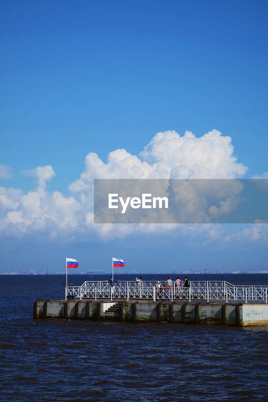 Russian flags on pier over sea against sky