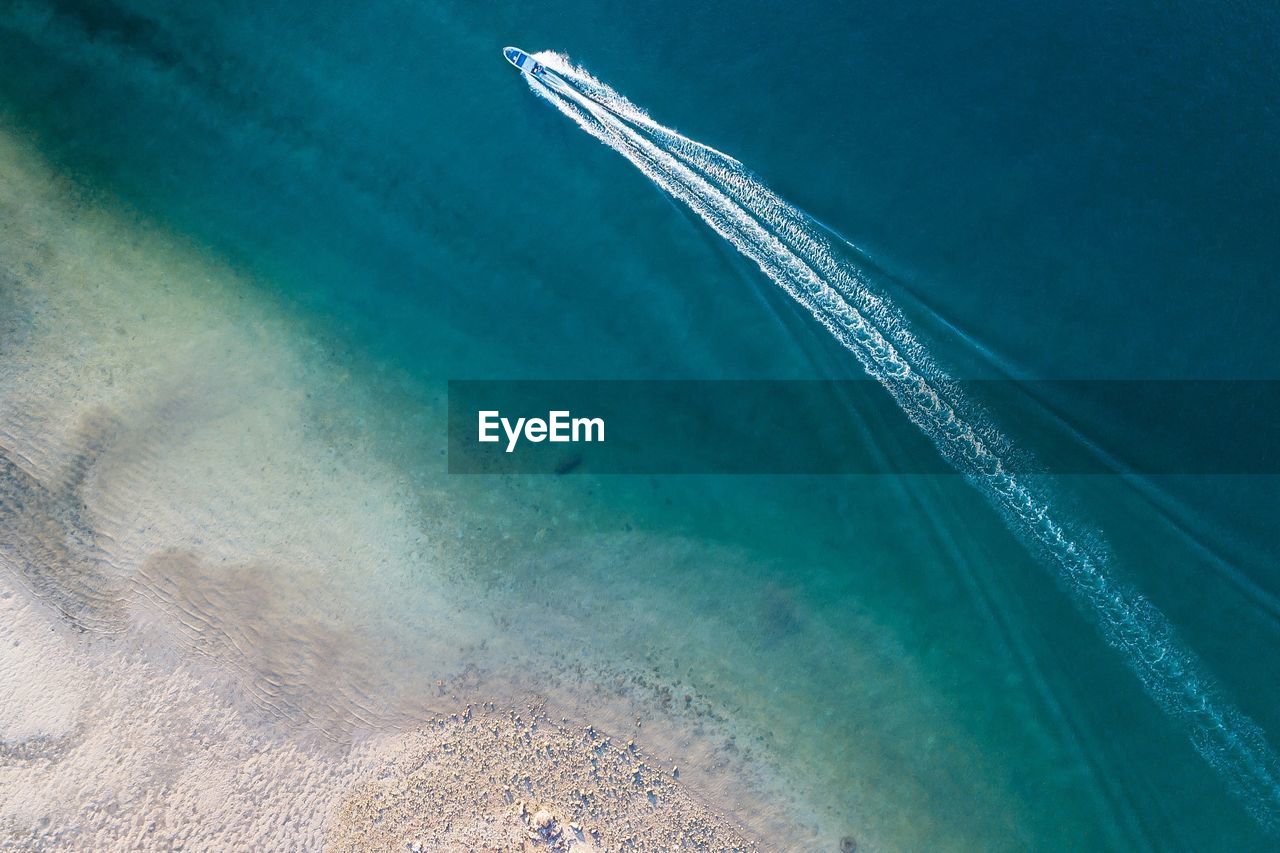 HIGH ANGLE VIEW OF SEA AND AIRPLANE FLYING IN BLUE SKY