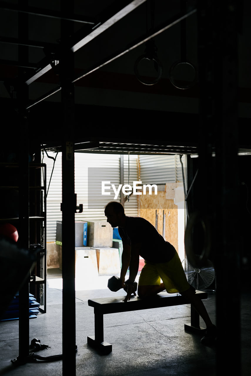 Young man working out in a indoors garage gym with dumbbell