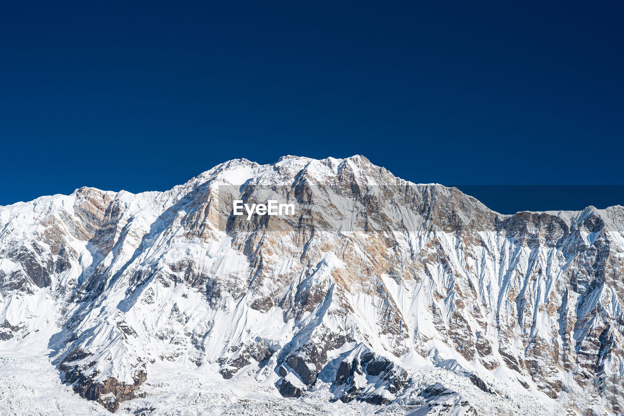 Scenic view of snowcapped mountains against clear blue sky