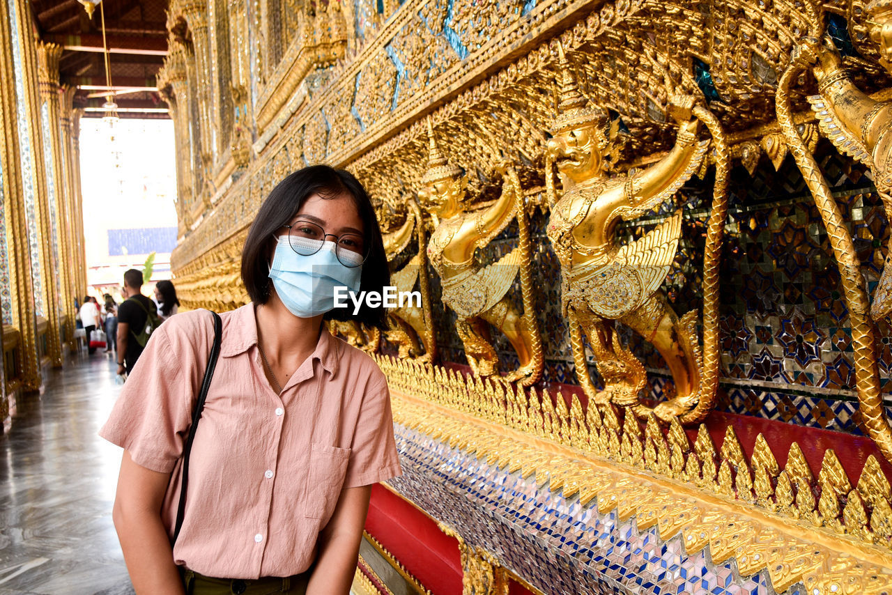 Portrait of woman wearing mask standing in temple