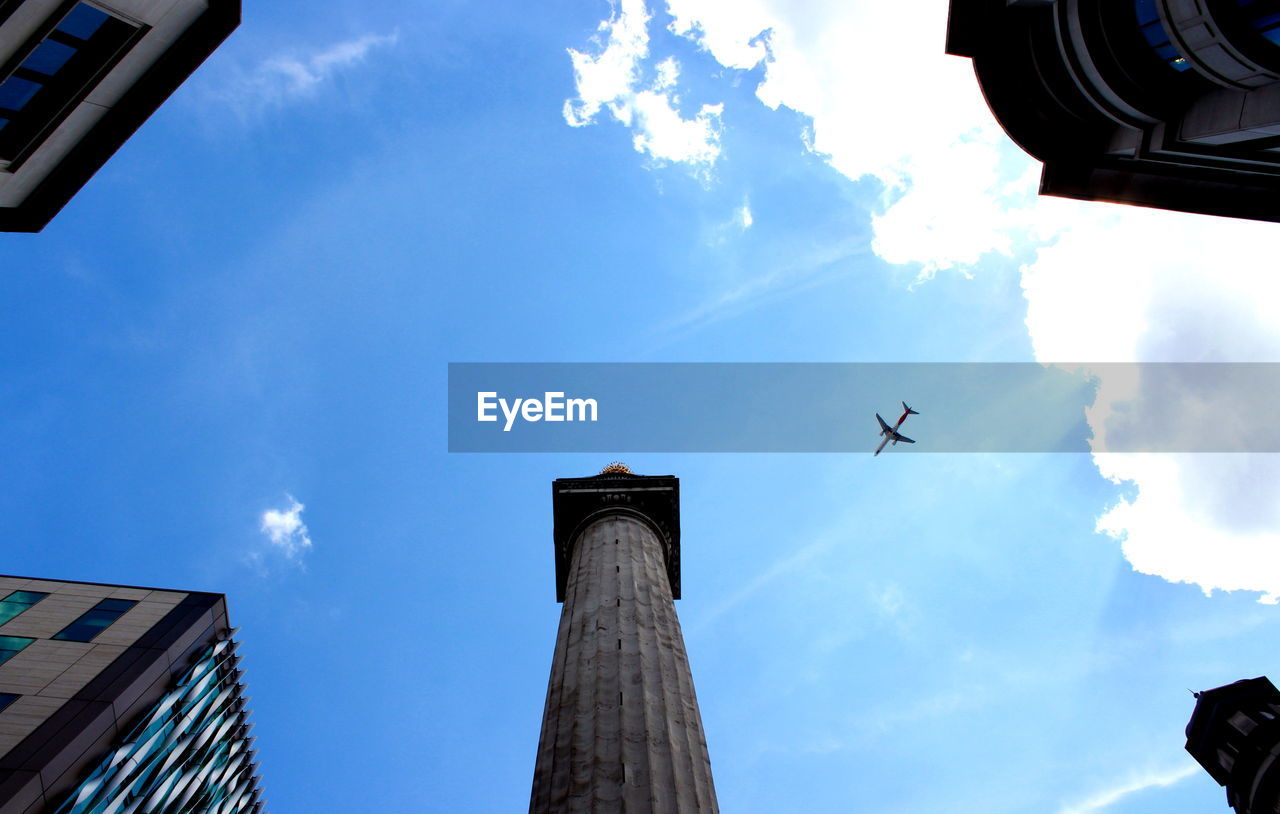 LOW ANGLE VIEW OF BUILDING AND AIRPLANE AGAINST SKY