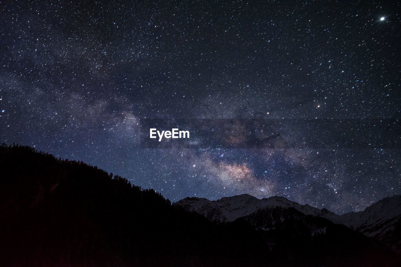 SCENIC VIEW OF MOUNTAINS AGAINST STAR FIELD AT NIGHT