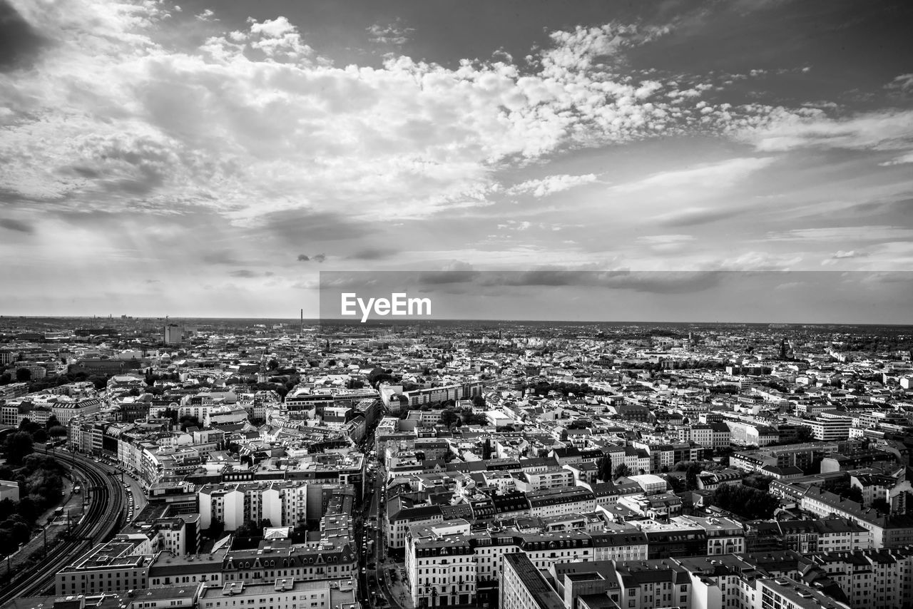 Aerial view of cityscape against cloudy sky