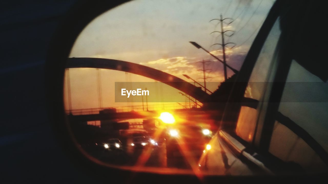 CLOSE-UP OF SILHOUETTE CAR ON ROAD AGAINST SUNSET