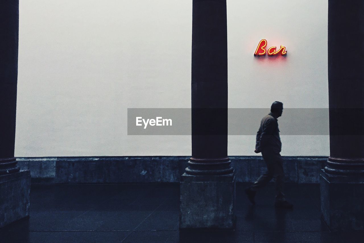 Man walking on sidewalk by bar