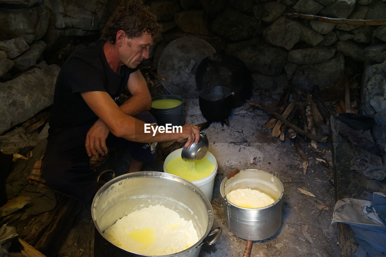 HIGH ANGLE VIEW OF MAN PREPARING FOOD AT KITCHEN