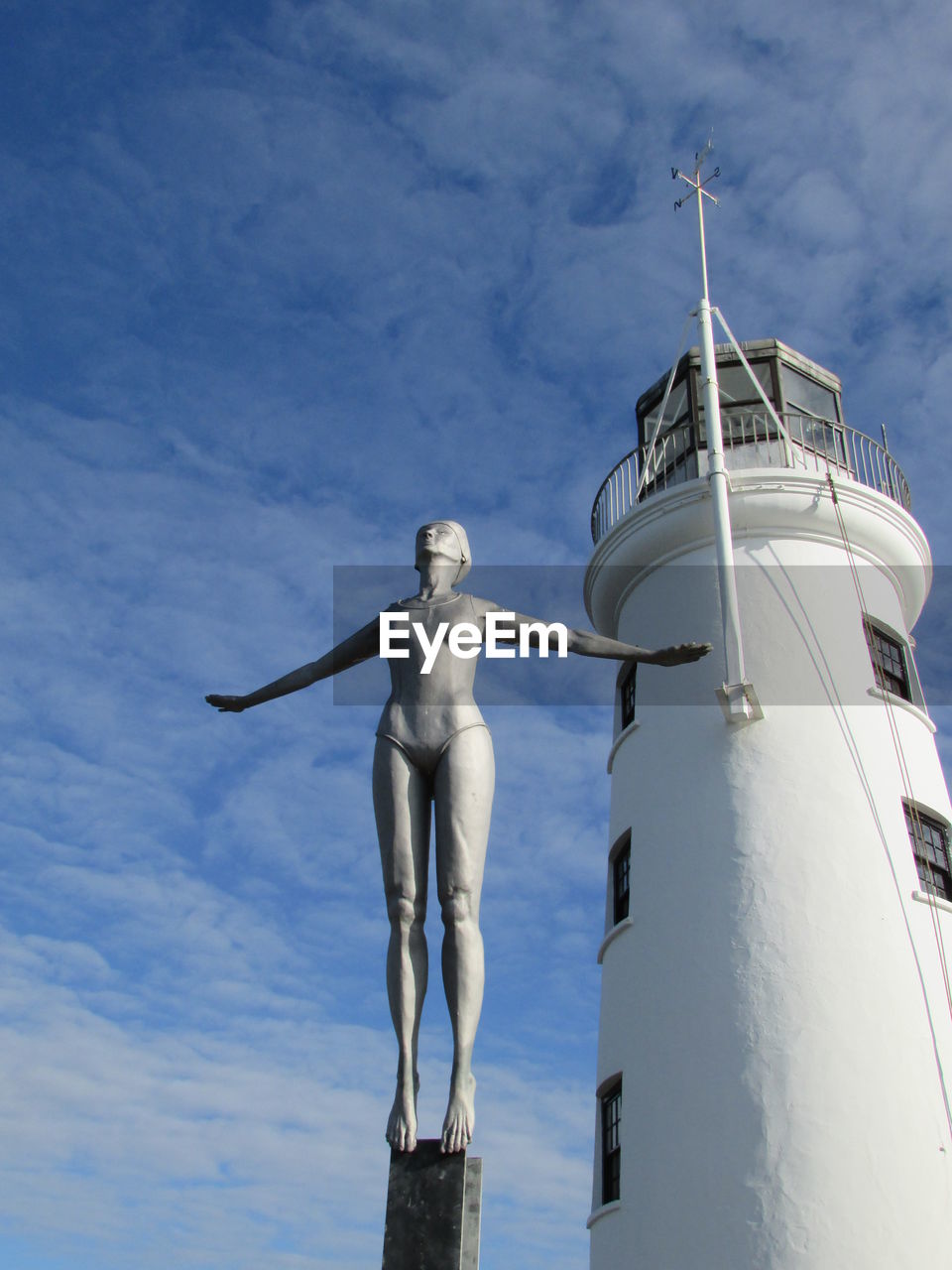 Low angle view of statue and lighthouse against sky