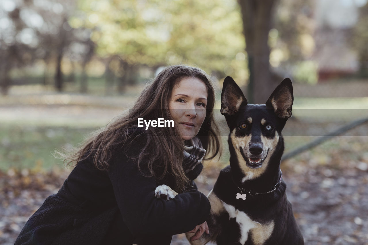 Side view portrait of smiling woman with dog at park