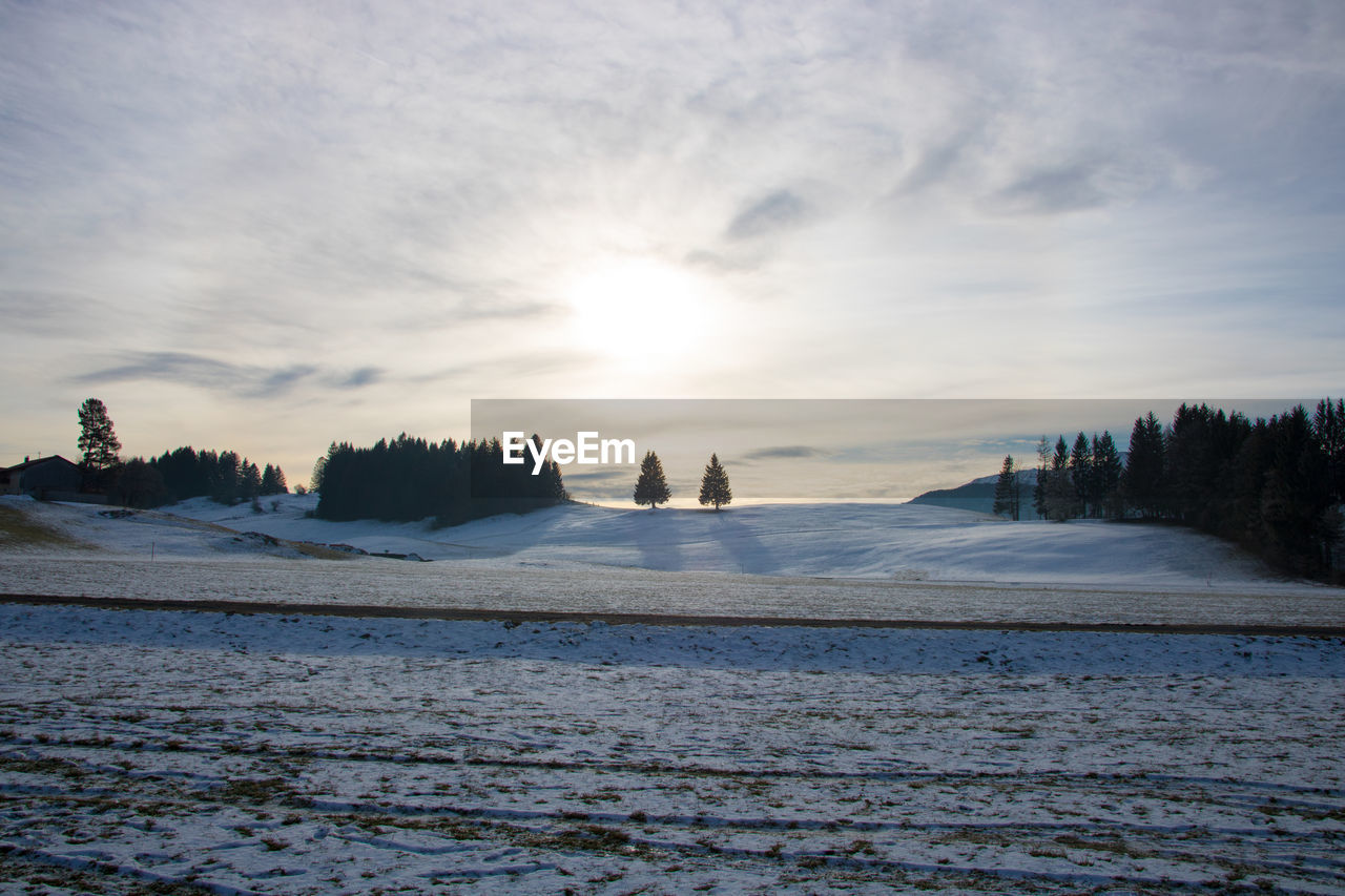 Scenic view of frozen landscape against sky during sunset