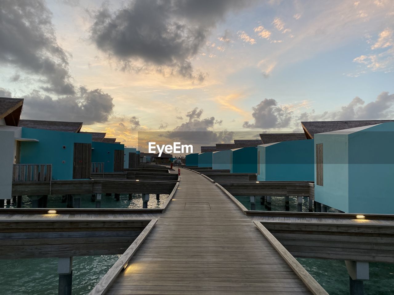 Pier amidst buildings against sky at sunset