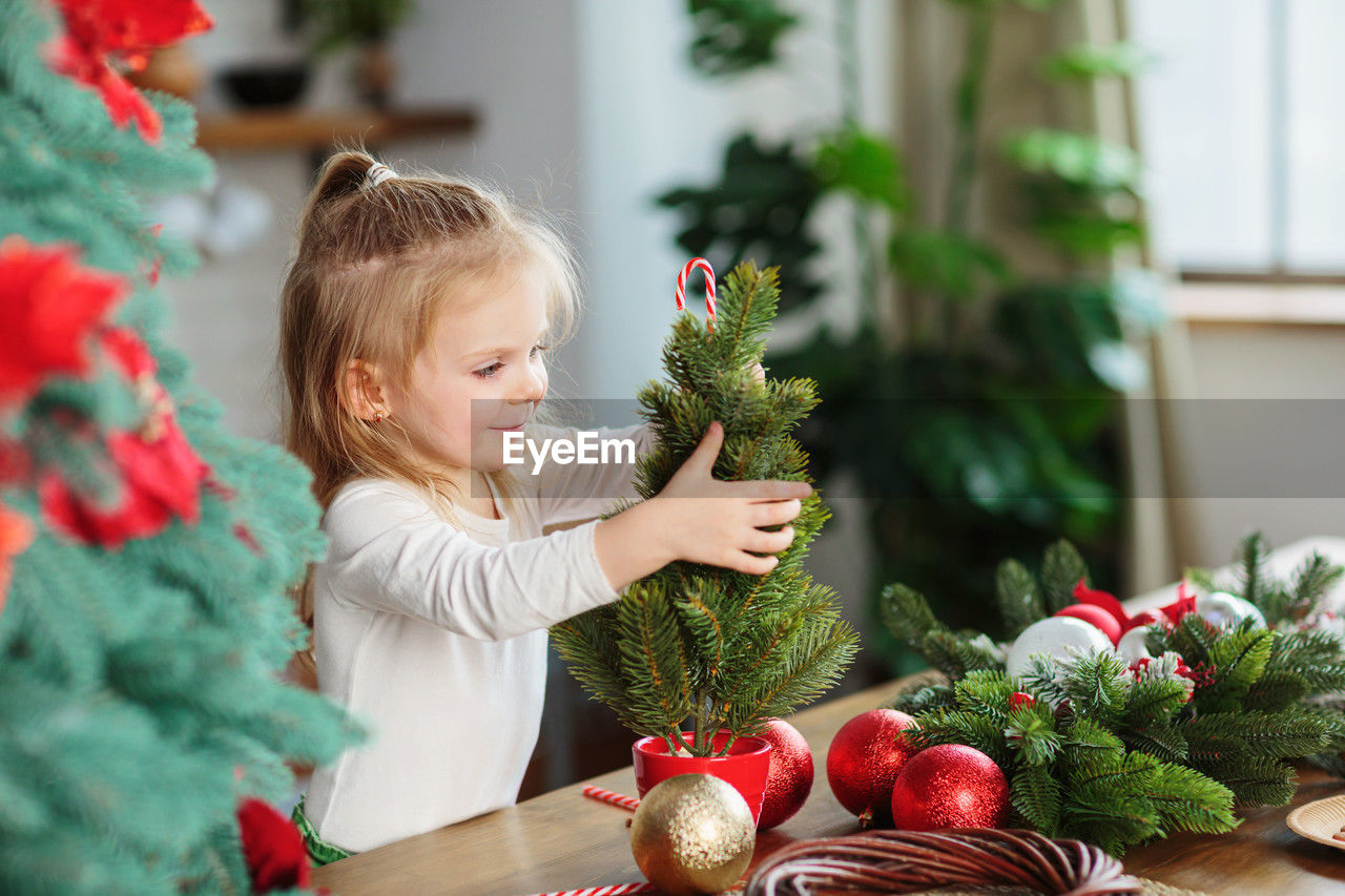 Little girl playing in kitchen with christmas tree and new years decor