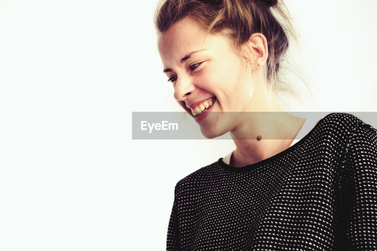 Smiling young woman standing against white background