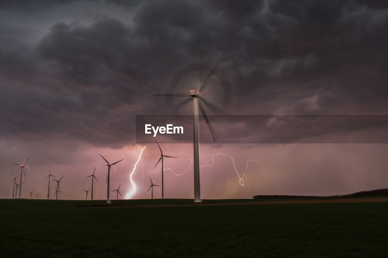 Wind turbines on field against sky