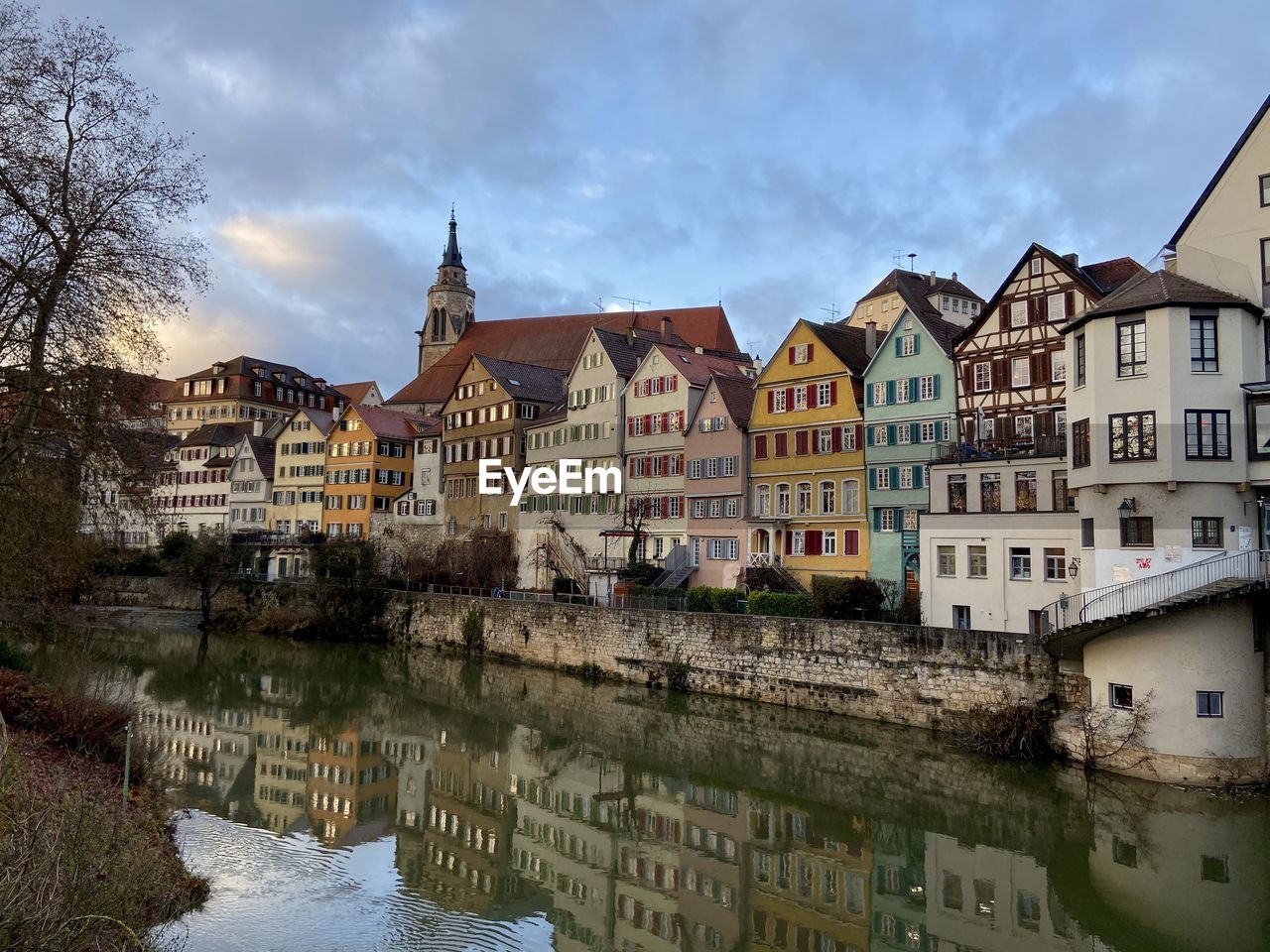 Buildings by river in town against sky