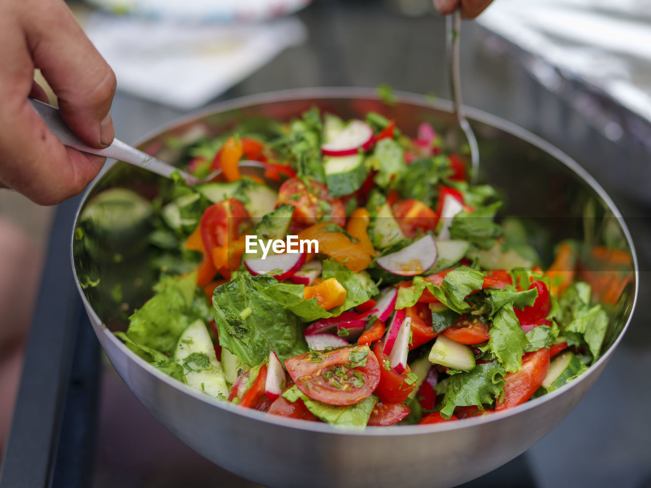 Selective focus of fresh chopped spring salad, man mixing salad, compilation of healthy food