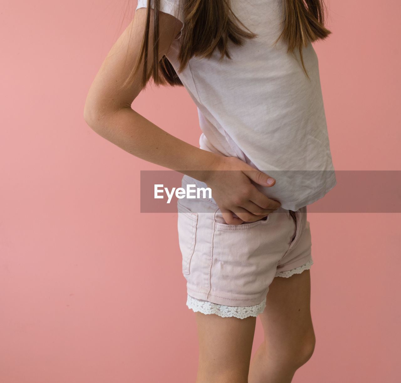 Midsection of girl standing against colored background