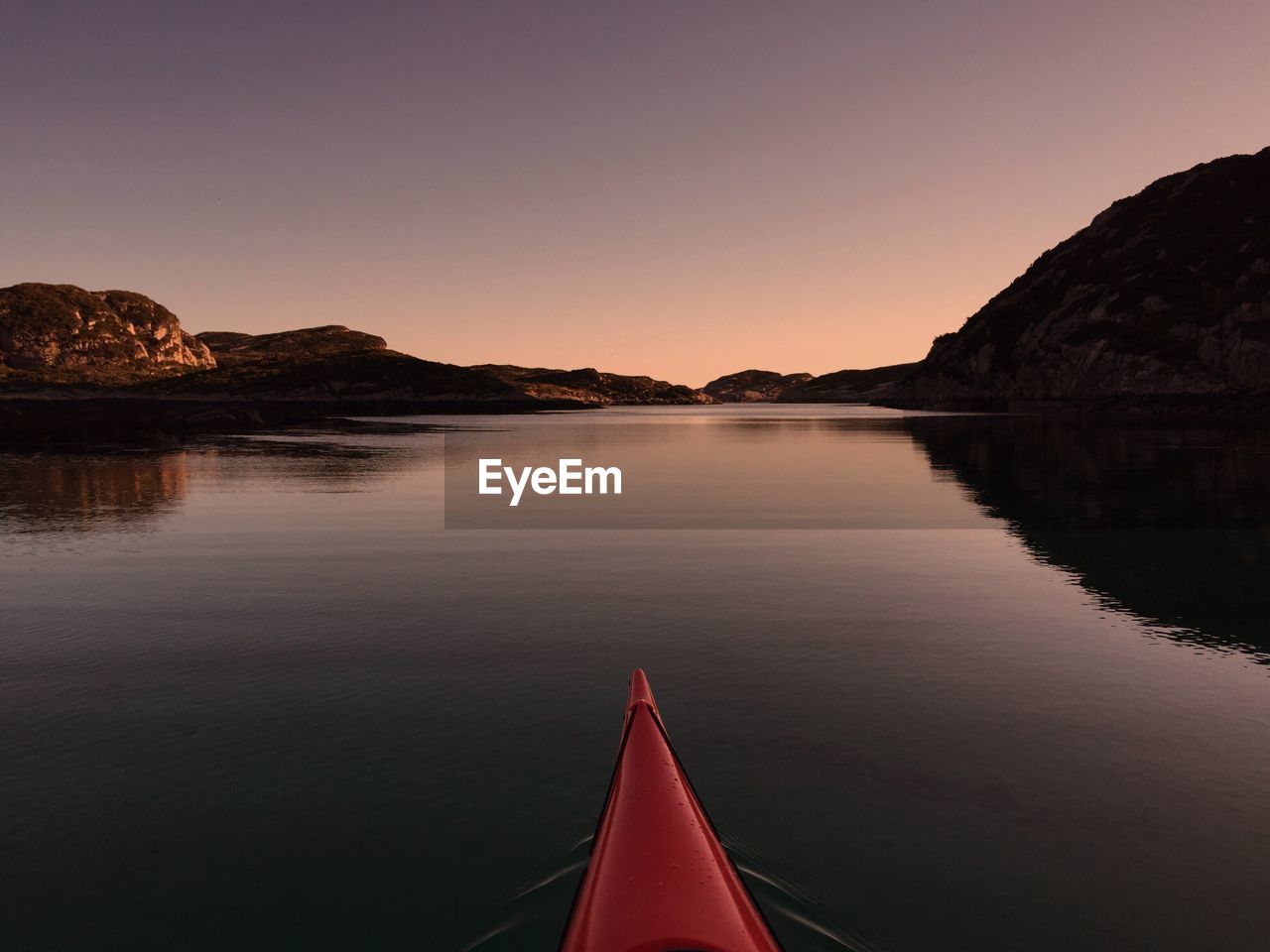 Cropped kayak on calm lake against sky during sunset