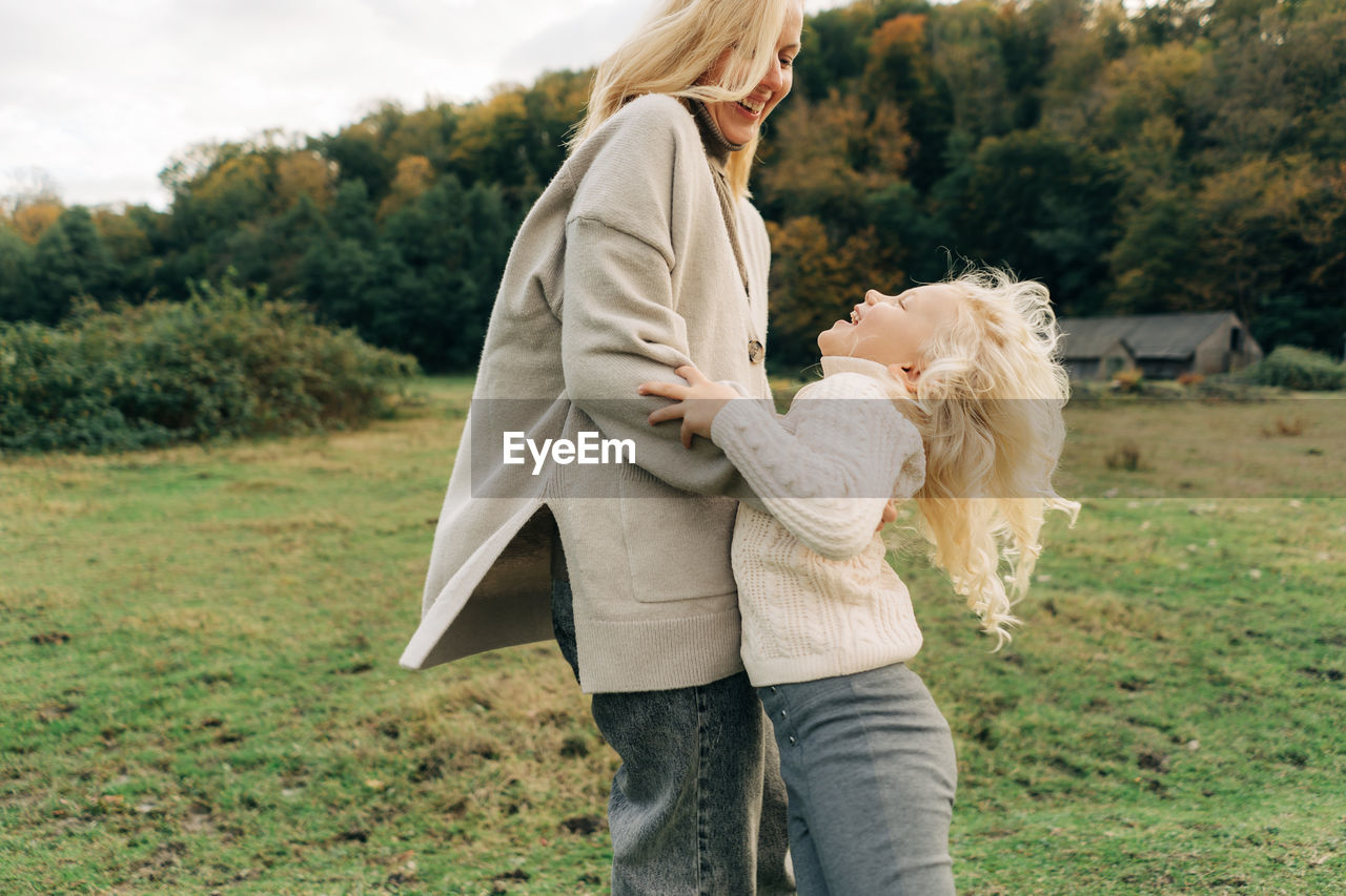 Mommy and little daughter have fun and hugging on a walk in the village.