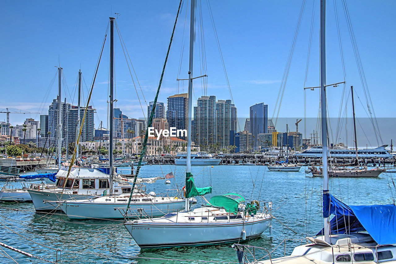 SAILBOATS MOORED IN HARBOR AT CITY