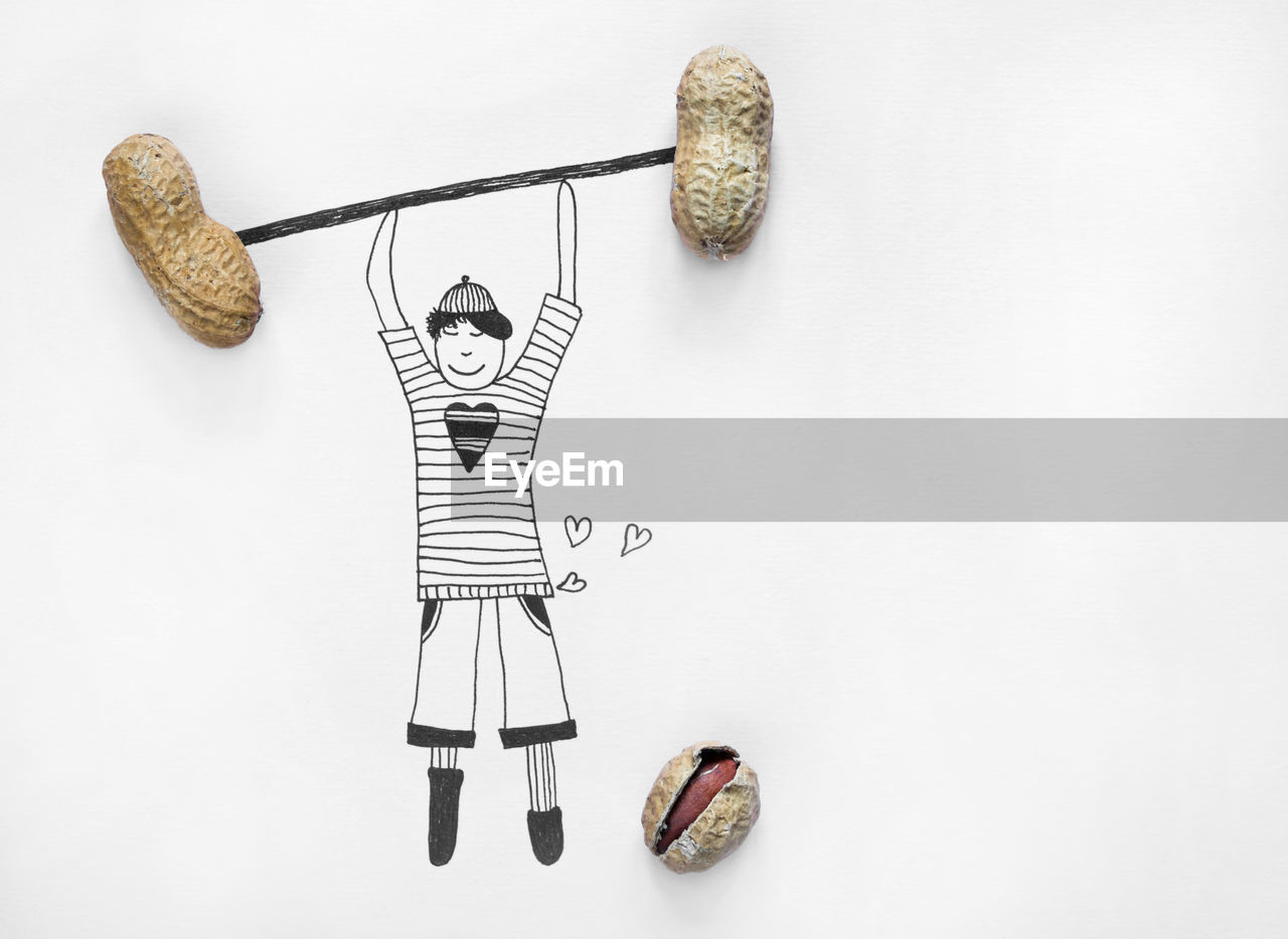 An illustration of a boy lifting dumbbells from real peanuts