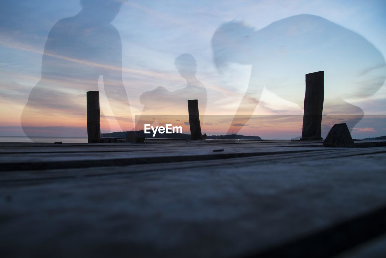 Double exposure of people on pier against sky during sunset