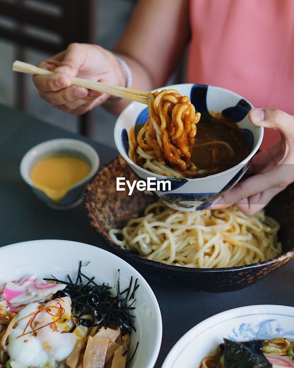 Midsection of woman having tsukemen with cheese and curry at restaurant