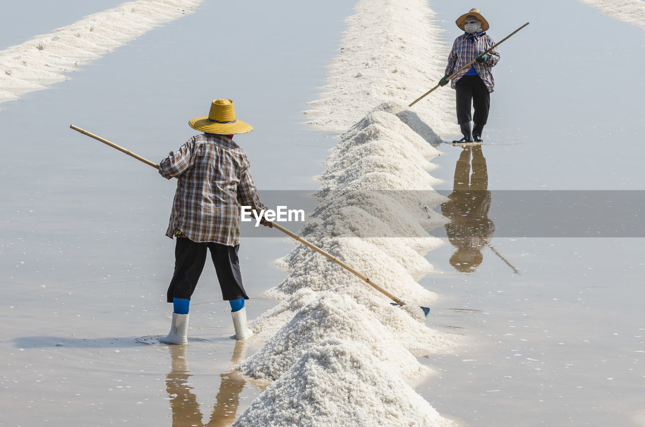 Farmers are using the tools to scoop the salt into a pile in salt garden at phetchaburi, thailand.