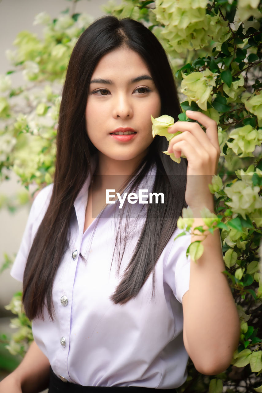 PORTRAIT OF A BEAUTIFUL YOUNG WOMAN AT FLOWER