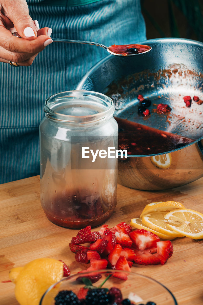 Fruit canning at home. woman pouring cooked jam into sterile jars. fruit preservation.