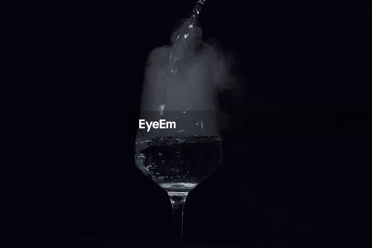 CLOSE-UP OF WINE GLASS AGAINST BLACK BACKGROUND