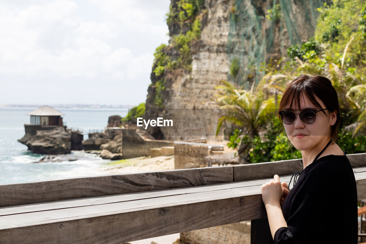 PORTRAIT OF WOMAN WITH SUNGLASSES IN BACKGROUND