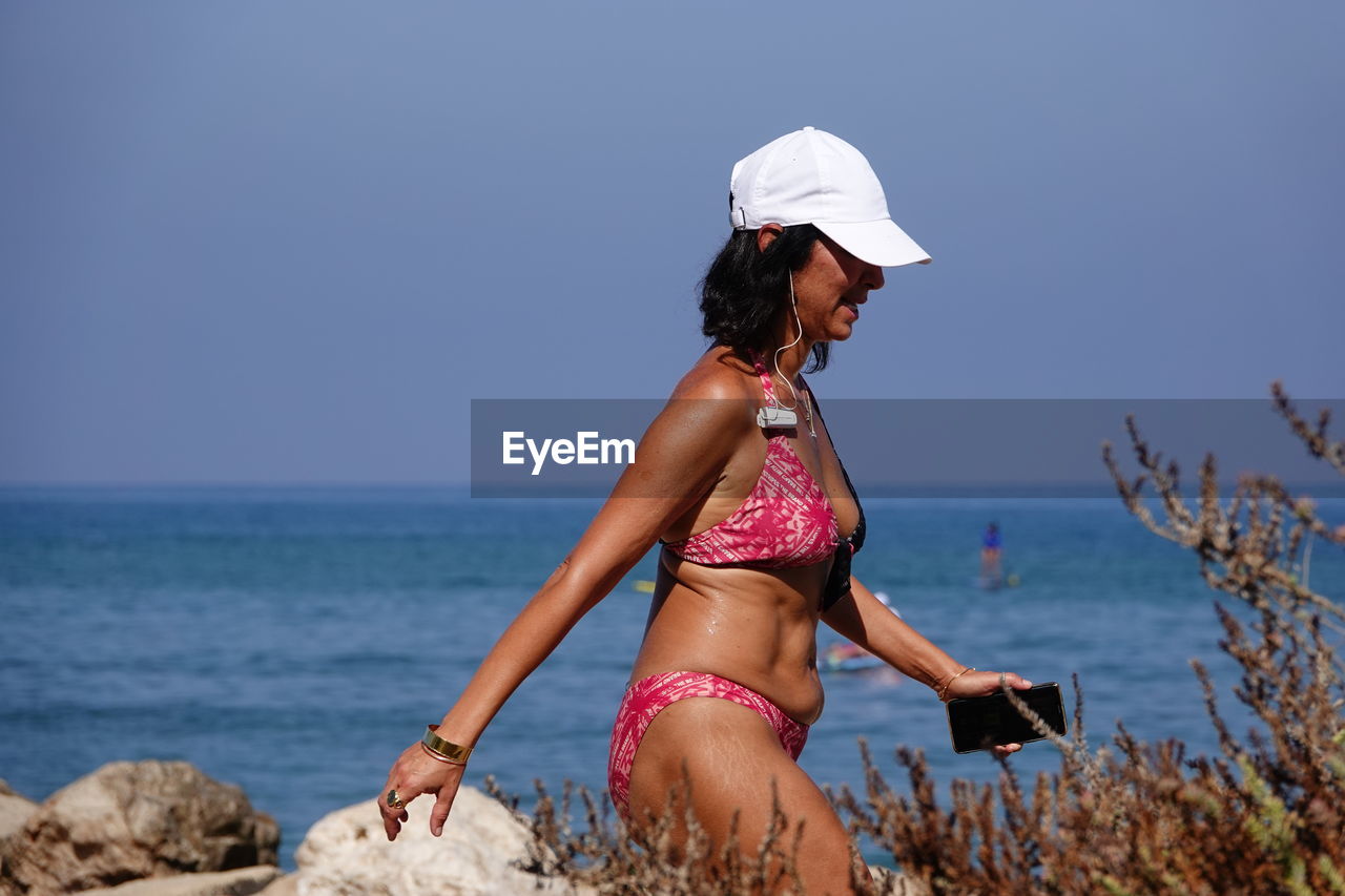 Woman on beach by sea against sky