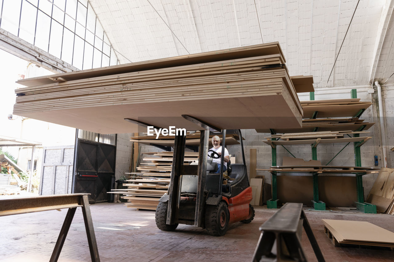 Carpenter using forklift truck in factory