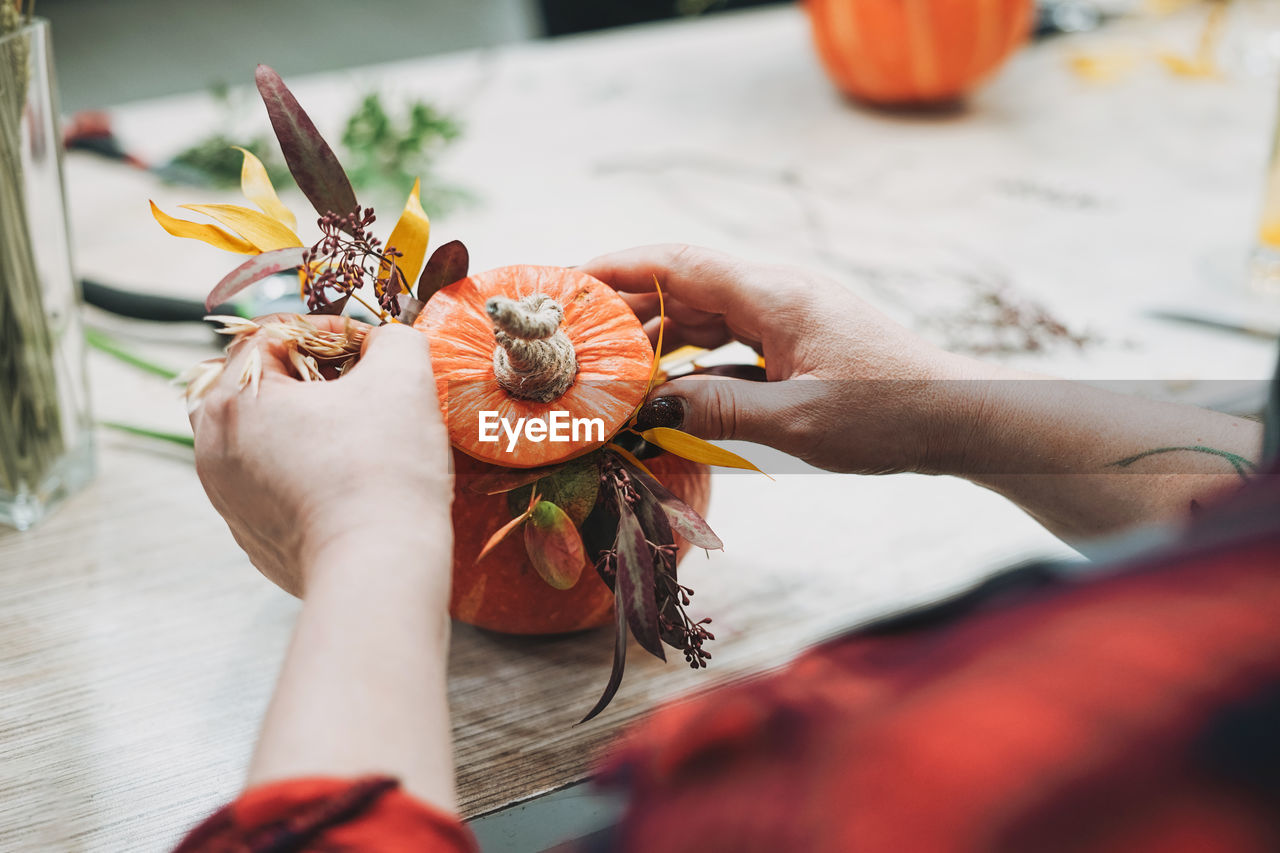 Cropped image of woman decorating pumpkin