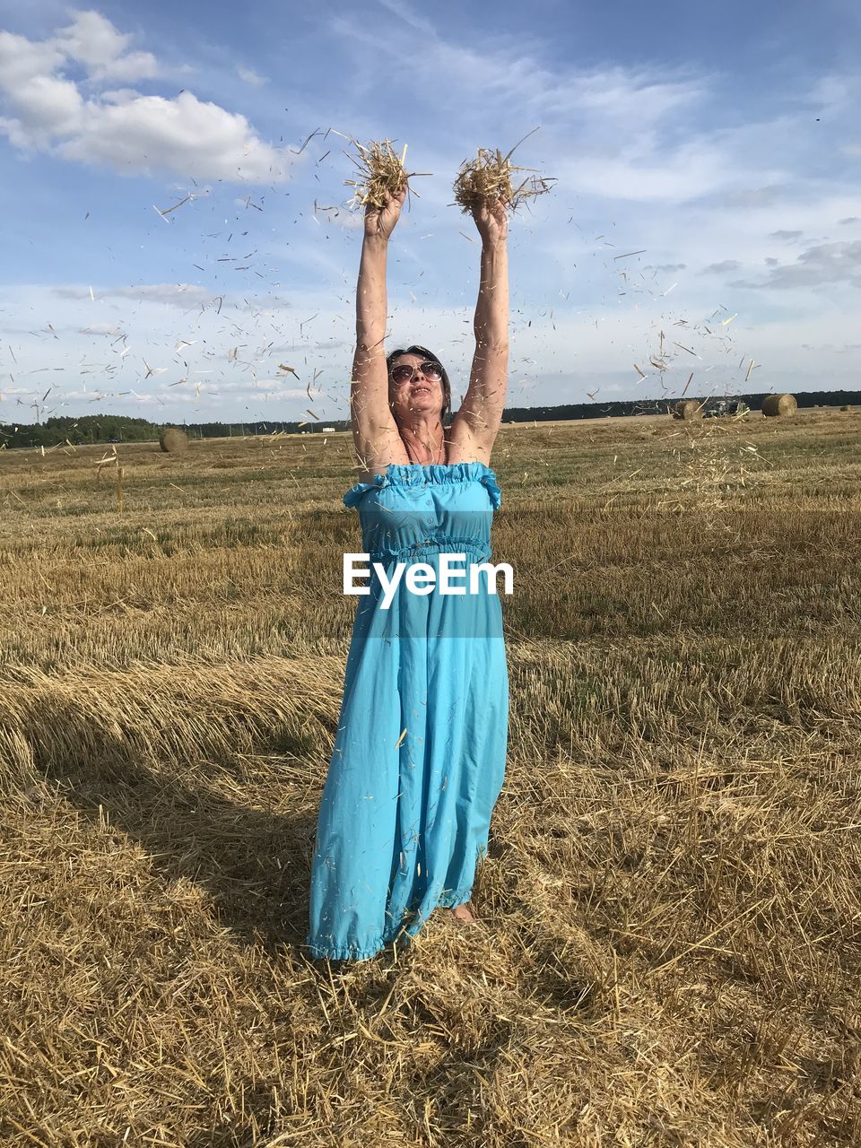 FULL LENGTH OF HAPPY WOMAN STANDING ON FIELD