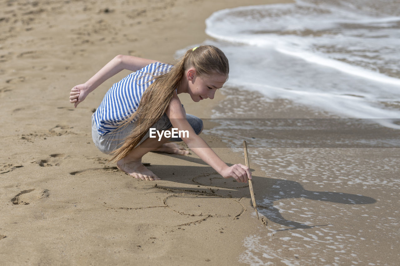 Full length of playful girl on shore at beach