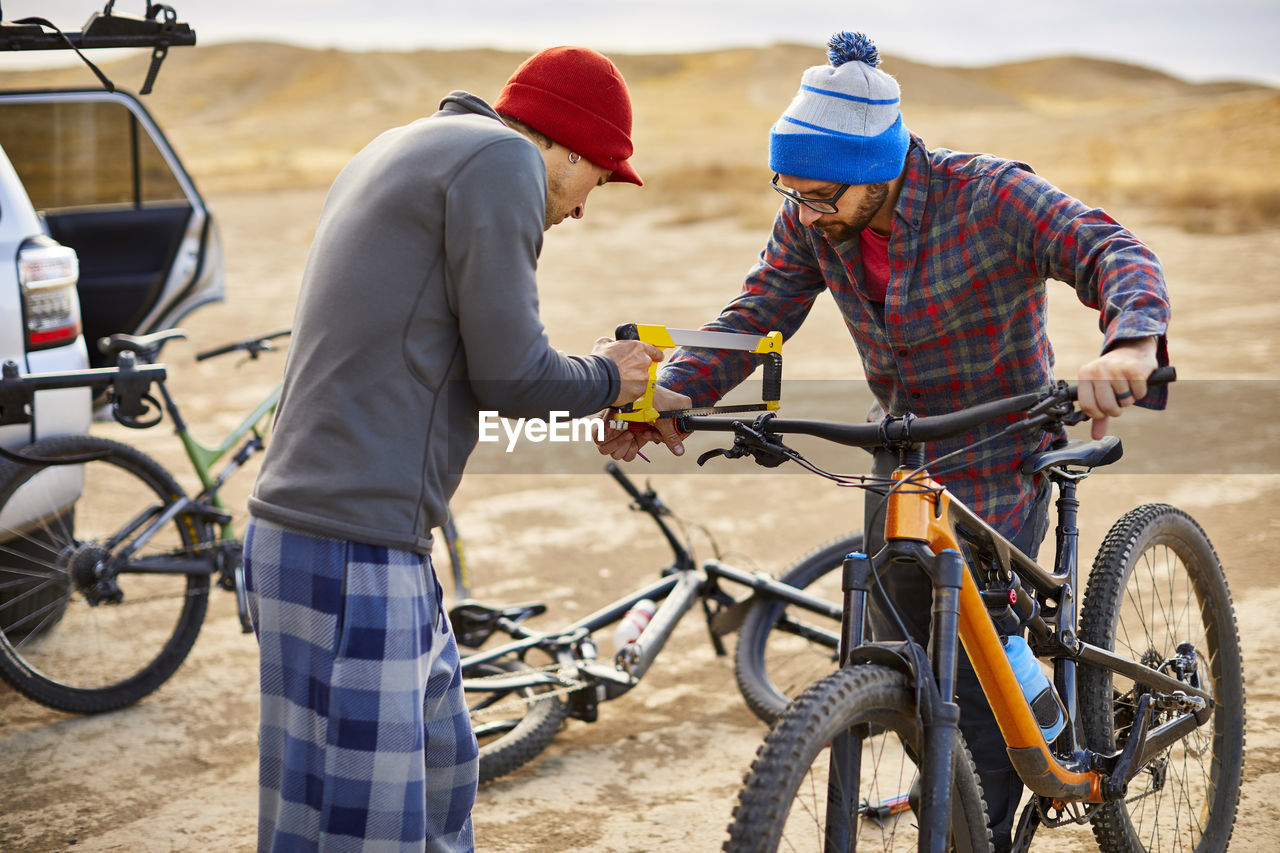 Two mountain bikers working together to modify handlebars.