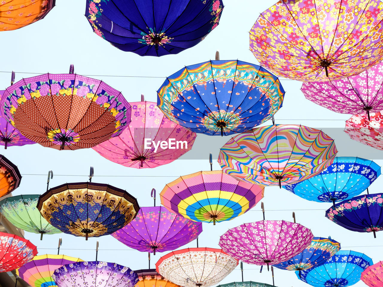 Low angle view of colorful umbrellas hanging against sky