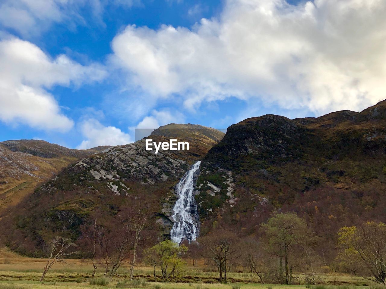 SCENIC VIEW OF WATERFALL AGAINST SKY