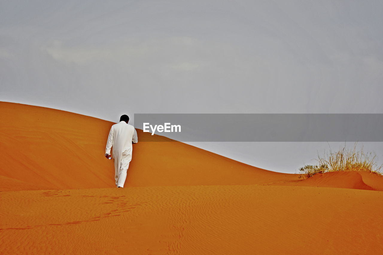 REAR VIEW OF MAN STANDING ON DESERT