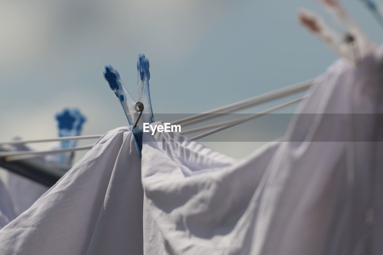 Low angle view of clothes hanging on rope against sky