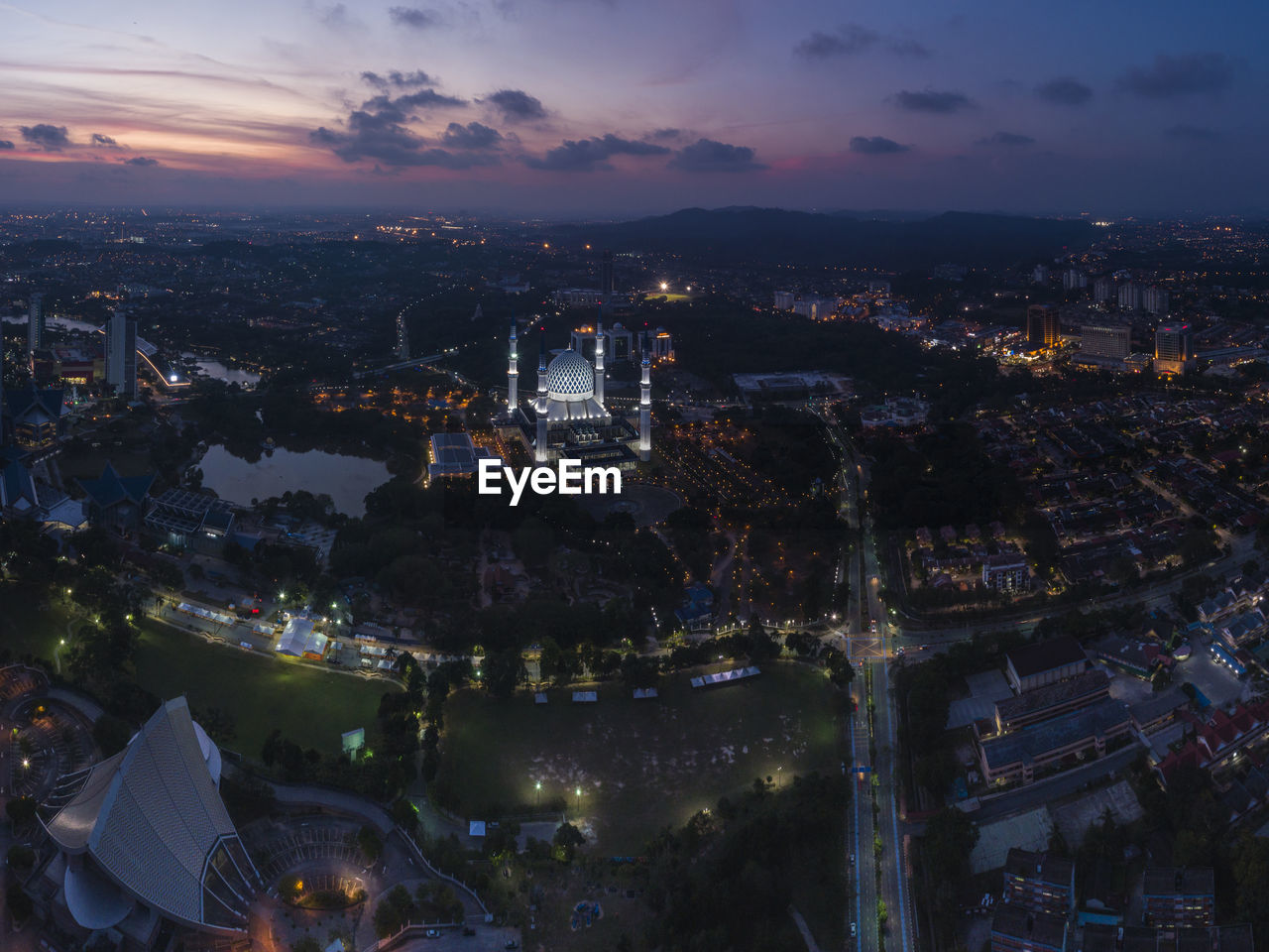 High angle view of illuminated city against sky at sunset