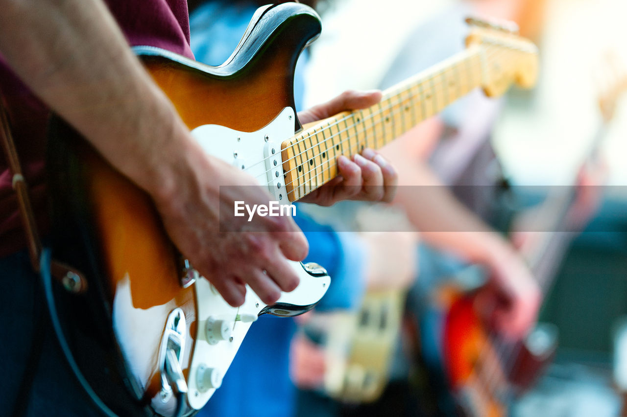 Midsection of man playing guitar