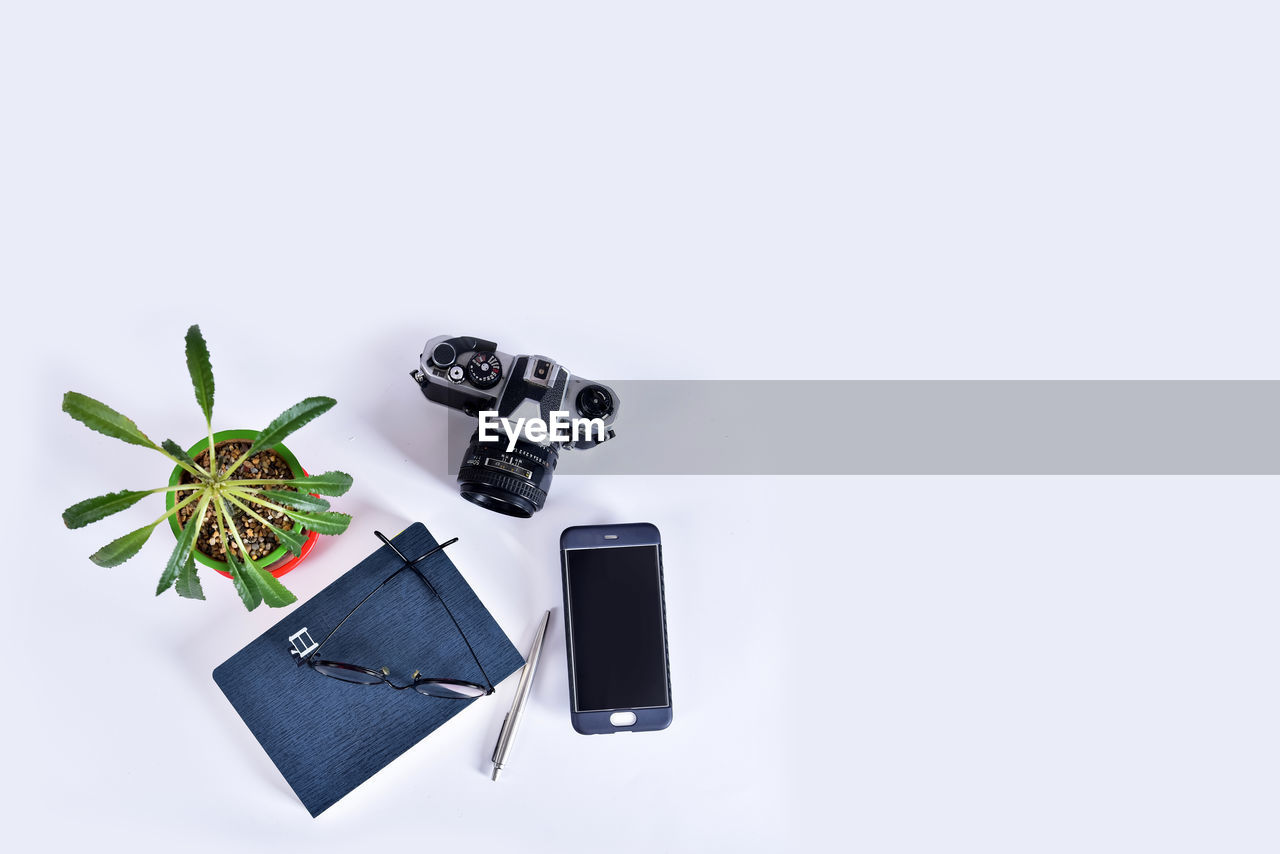 HIGH ANGLE VIEW OF CAMERA ON PLANT AGAINST GRAY BACKGROUND