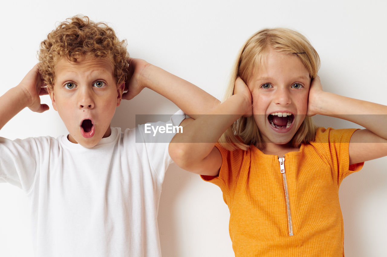 Portrait of smiling sibling against white background